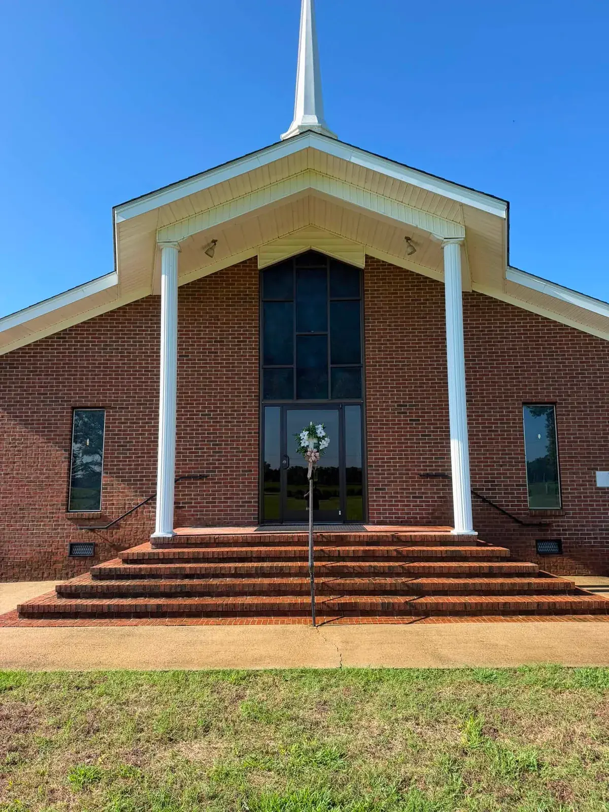 Brick church with white entrance columns, brick steps, and a steeple