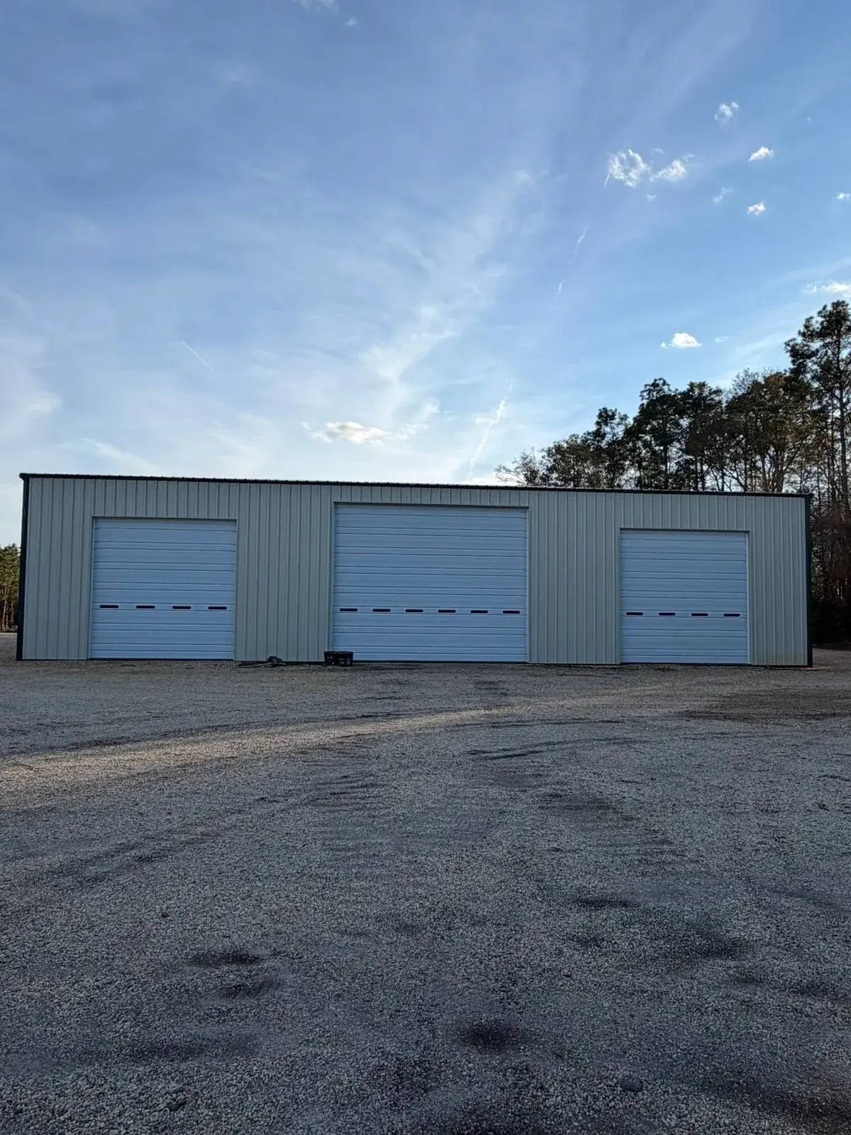 Metal shop building with three white overhead doors