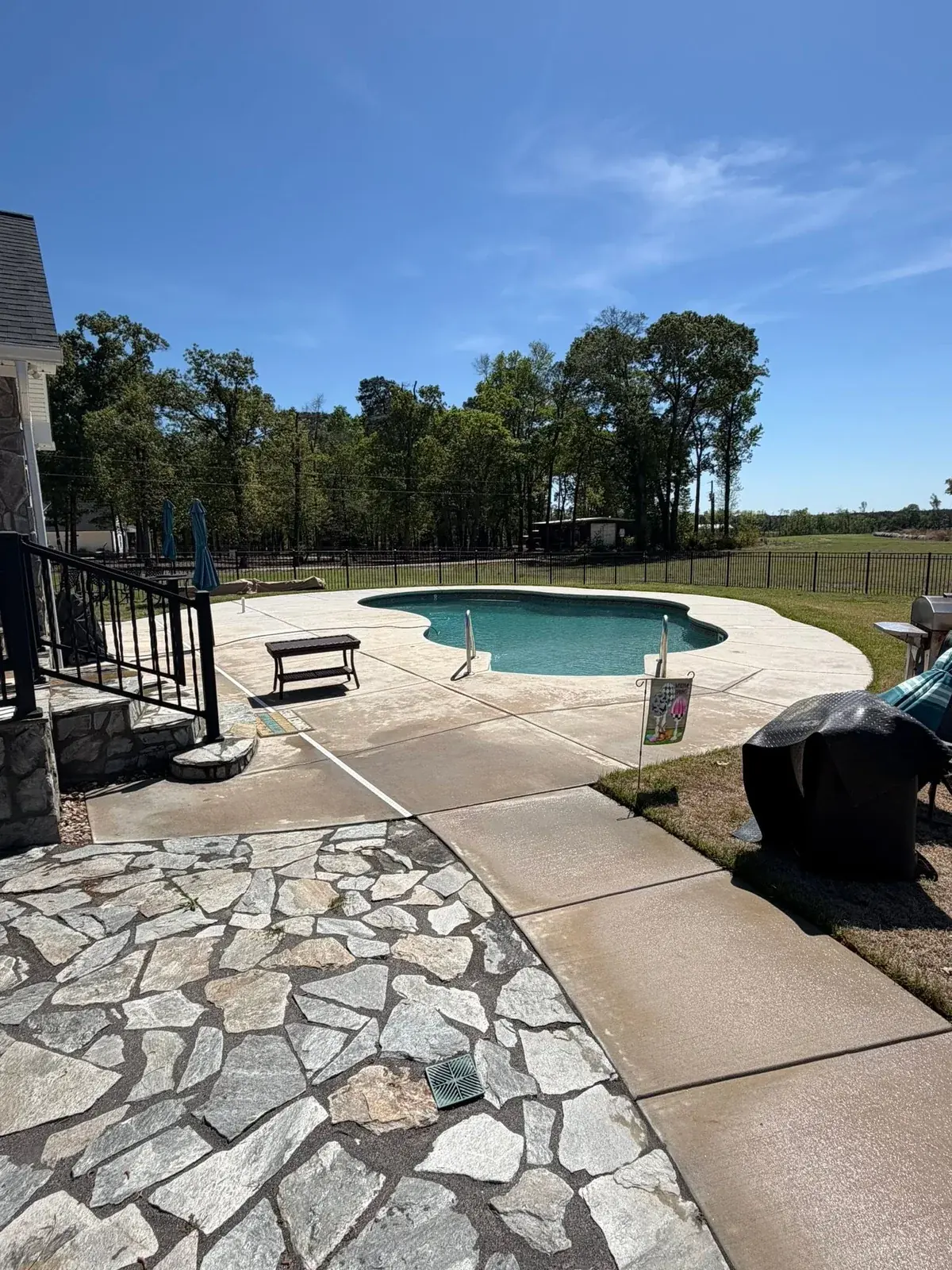 Concrete pool surround, connecting walkway, and stone patio from a Reaves ProWash project