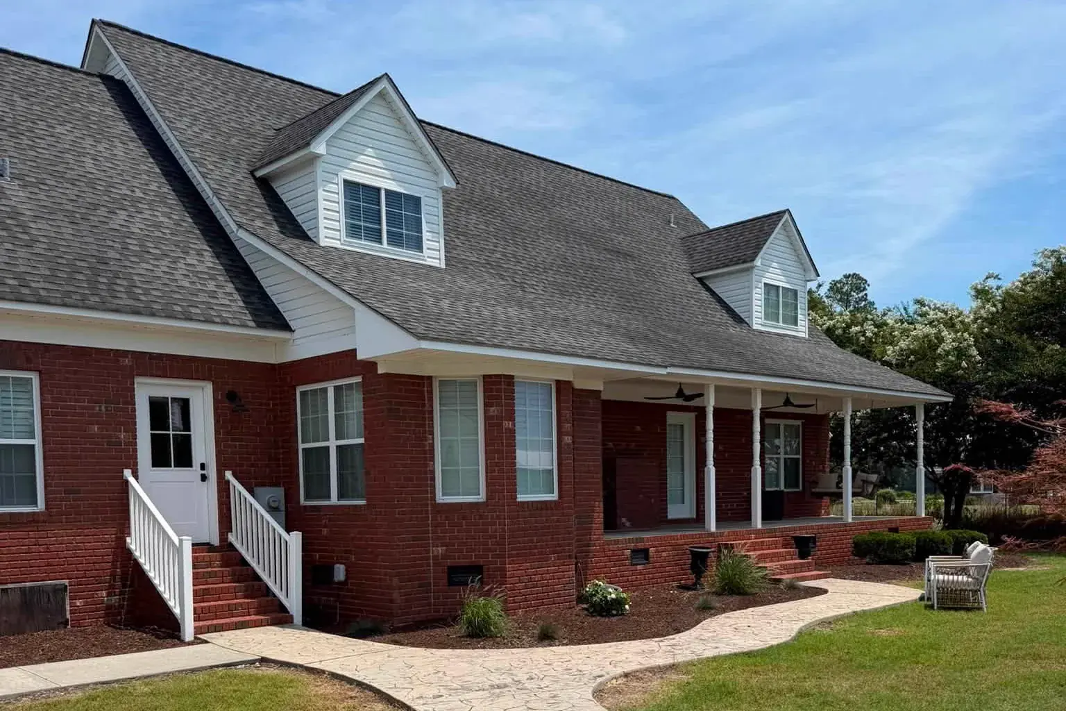 Brick home with white trim and a freshly cleaned stamped concrete walkway, a Reaves ProWash job