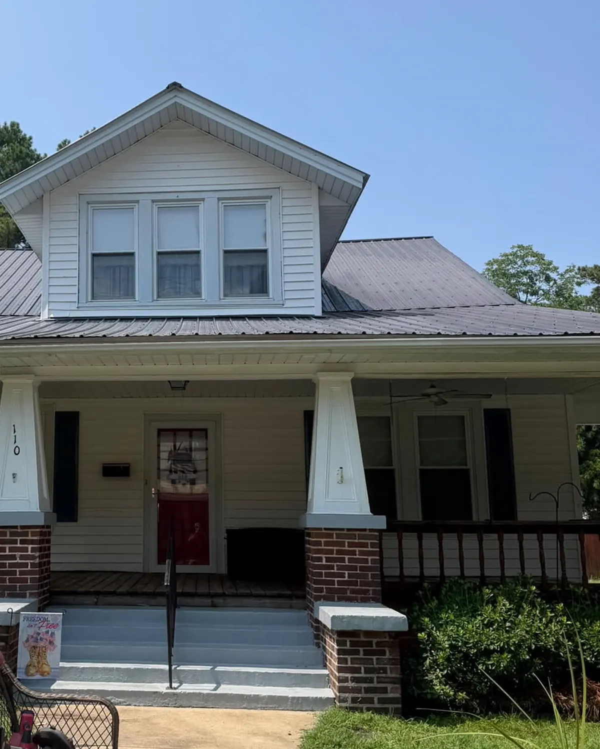 Metal roof, white porch columns, and siding on a bungalow